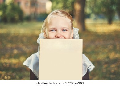 Portrait of a happy child hiding behind a book.