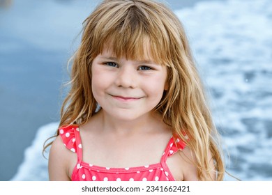 Portrait of Happy Child, Little Preschool Girl in Swimmsuit Running And Jumping In The Waves During Summer Vacation On Exotic Tropical Beach. Family Journey On Ocean Coast.