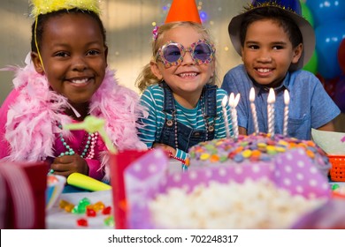 Portrait of happy children by birthday cake at table during party - Powered by Shutterstock