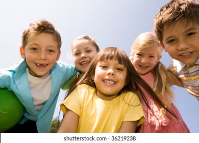 Portrait Of Happy Children Embracing Each Other And Laughing With Pretty Girl In Front