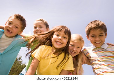 Portrait Of Happy Children Embracing Each Other And Laughing With Pretty Girl In Front