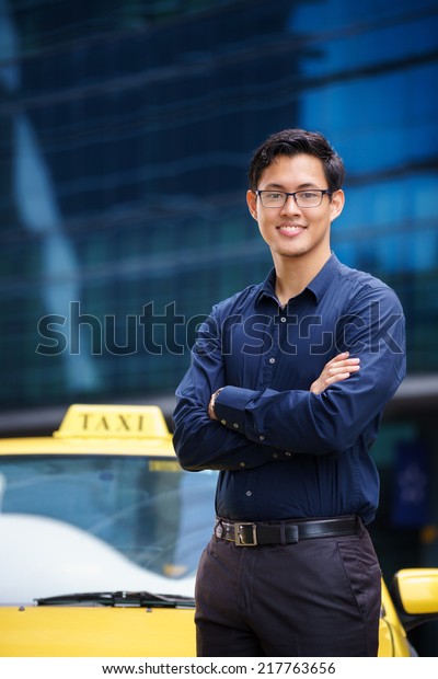 Portrait of happy\
chinese taxi driver leaning on yellow car with arms crossed,\
smiling and looking at\
camera
