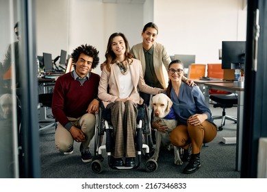 Portrait of happy colleagues with assistance Labrador Retriever dog in the office looking at camera. One of them is in a wheelchair. - Powered by Shutterstock