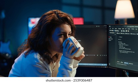 Portrait of happy computer engineer enjoying hot tea while implementing security measures to protect company systems and data. Joyful IT worker holding coffee mug and debugging code, camera A - Powered by Shutterstock