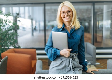 Portrait Of Happy Confident Businesswoman In Eyaglasses And Stylish Formal Suit. Middle Aged Successful Female Leader Looking Directly At The Camera, Smiling, Holding Laptop In Arms