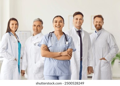 Portrait of a happy confident successful team of young doctors in uniform looking cheerful at camera and smiling while standing in hospital or clinic. Medical staff and health care concept. - Powered by Shutterstock