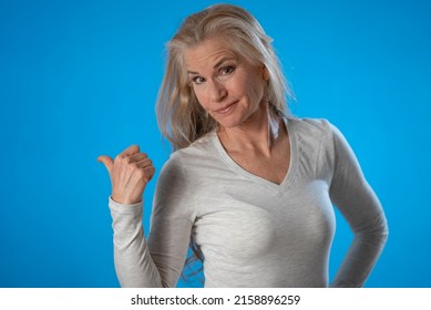 Portrait Of Happy Confused Mature Woman Thinking, Isolated On Solid Blue Background Studio With Copy Space.