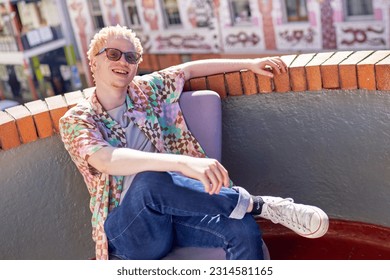 Portrait happy, cool young albino man sitting in armchair on sunny urban rooftop - Powered by Shutterstock