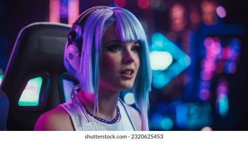 Portrait of a Happy Cosplay Girl in Headphones Talking with Friends Online on a Computer. Stylish Streamer or Video Gamer Chatting with Internet Fans in Futuristic Cyberpunk Studio