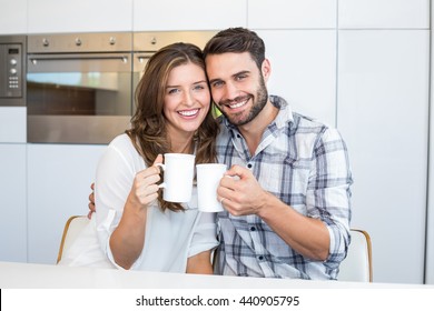 Portrait Of Happy Couple Drinking Coffee By Table At Home