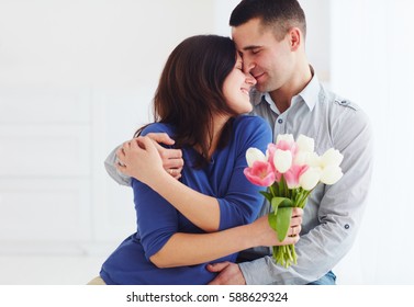 portrait of happy couple, husband and wife with spring flower bouquet