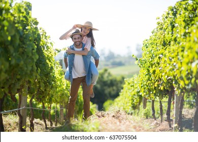 Portrait of happy couple piggybacking at vineyard during sunny day - Powered by Shutterstock