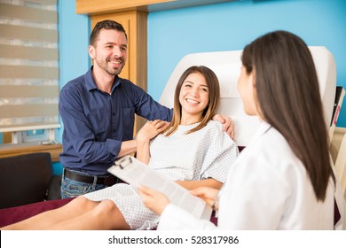 Portrait Of A Happy Couple Receiving Good News From A Doctor And Feeling Relieved In A Hospital Room