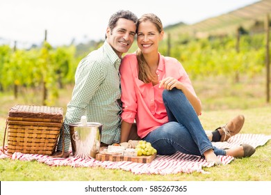 Portrait of happy couple relaxing on a blanket in vineyard - Powered by Shutterstock