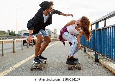 Portrait of happy couple riding skateboards and having fun outdoors. Teenager happiness concept - Powered by Shutterstock