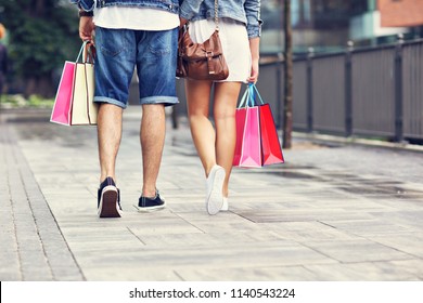 Portrait of happy couple with shopping bags after shopping in city