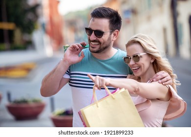 Portrait Of Happy Couple With Shopping Bags After Shopping In City.