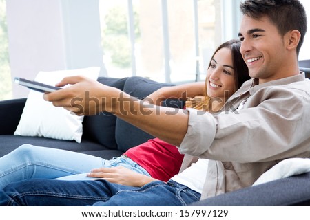 Portrait of happy couple sitting on sofa and watching television together
