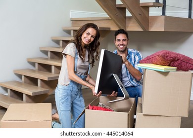 Portrait Of Happy Couple Unpacking Computer From Cardboard Box At Home