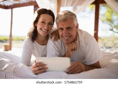 Portrait of happy couple using digital tablet on bed during morning