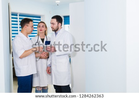 Portrait of happy cowerkers with clipboard while standing at hospital