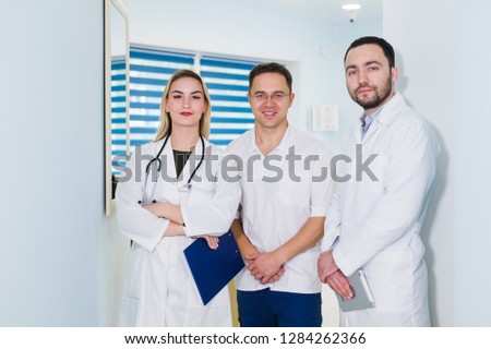 Portrait of happy cowerkers with clipboard while standing at hospital