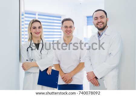 Portrait of happy cowerkers with clipboard while standing at hospital