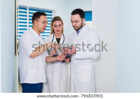 Portrait of happy cowerkers with clipboard while standing at hospital
