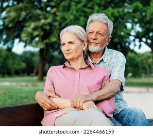 Portrait of happy ctive senior couple daydreaming and relaxing sitting on a bench in park outdoors - Shutterstock ID 2284466159