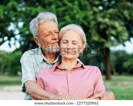 Portrait of happy ctive senior couple daydreaming and relaxing sitting on a bench in park outdoors