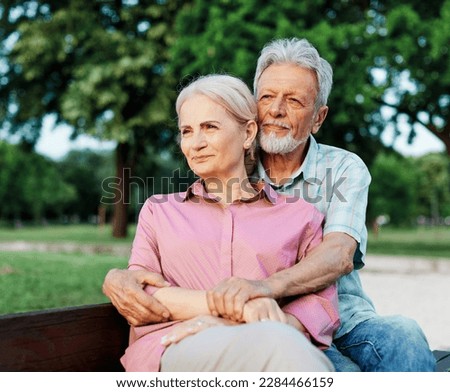 Portrait of happy ctive senior couple daydreaming and relaxing sitting on a bench in park outdoors