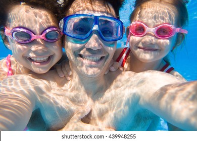 Portrait of a happy dad with two young daughters under water. Selfies - Powered by Shutterstock