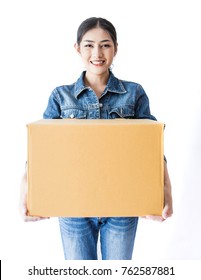 Portrait of happy delivery asian woman wearing jeans her hands holding cardboard box isolated on white background, young asian woman carry brown box moving house delivery service concept