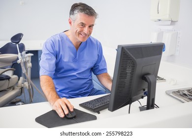 Portrait Of A Happy Dentist Using Computer In Dental Clinic