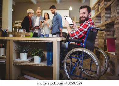 Portrait of happy disabled businessman using digital tablet at desk in creative office - Powered by Shutterstock