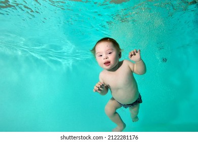 Portrait Of A Happy Disabled Child With Down Syndrome Who Swims And Plays Underwater In A Turquoise Water Pool. Close-up. Horizontal Orientation.