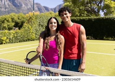 Portrait of happy diverse couple holding rackets and embracing on sunny outdoor tennis court. Summer, healthy lifestyle, sport, hobbies and vacations. - Powered by Shutterstock