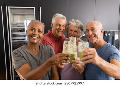 Portrait of happy diverse senior friends making a toast with healthy smoothies in kitchen. Senior lifestyle, active retirement, nutrition, health and wellbeing, unaltered. - Powered by Shutterstock