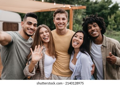 Portrait of happy diverse young friends posing near motorhome, having fun, being silly, showing different gestures, spending time together on camping trip. Cool summer vacation - Powered by Shutterstock