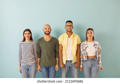 Portrait Of Happy Diverse Youth Group. Team Of Young Mixed Race Multi Ethnic People Wearing Casual Clothes Looking At Camera And Smiling Standing In Row Against Blue Studio Background