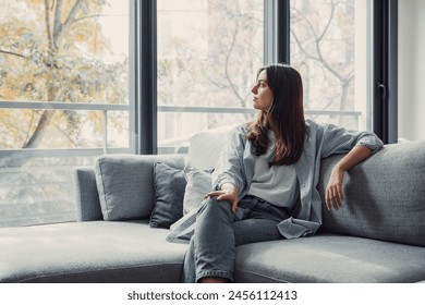 Portrait of happy dreamy young woman looking away, standing with folded arms in modern living room, visualizing future, recollecting good memories, planning weekend or thinking of problem solutions. - Powered by Shutterstock