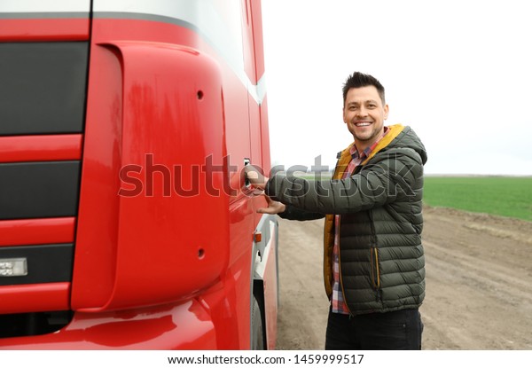 Portrait of happy driver opening door of modern\
truck outdoors