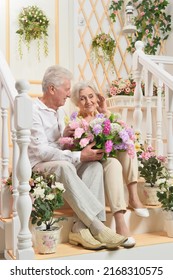 Portrait Of A Happy Elderly Couple On The Porch With Flowers