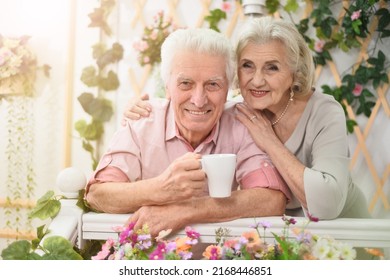 Portrait Of A Happy Elderly Couple On The Porch With Flowers