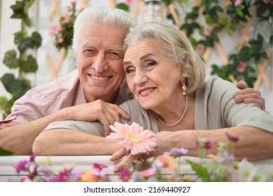 Portrait Of A Happy Elderly Couple On The Porch With Flowers