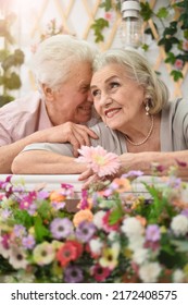 Portrait Of A Happy Elderly Couple On The Porch With Flowers