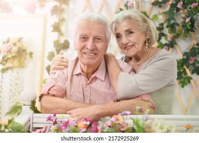 Portrait Of A Happy Elderly Couple On The Porch With Flowers