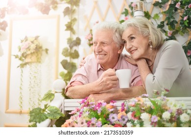 Portrait Of A Happy Elderly Couple On The Porch With Flowers