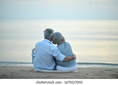 Portrait of happy elderly couple resting on tropical beach