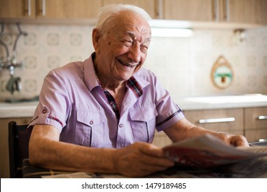 Portrait of a happy elderly gentleman reading newspapers and smiling with joy, morning ritual in the kitchen  - Powered by Shutterstock